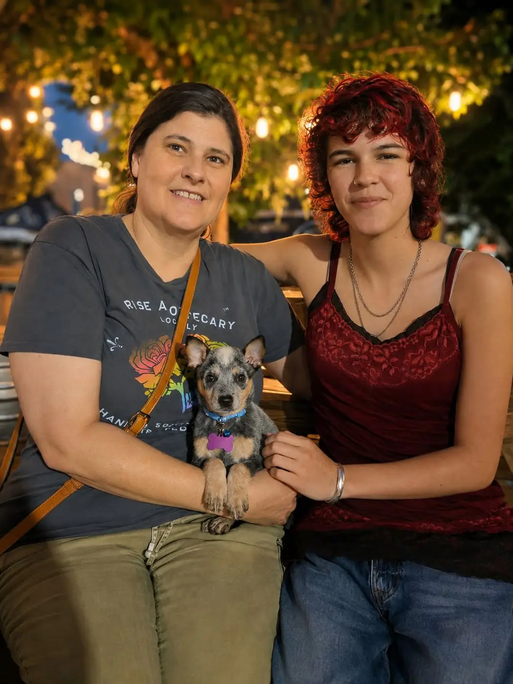 Dean's new adopters smiling together outdoors at night, with Dean the Blue Heeler puppy on a leash between them