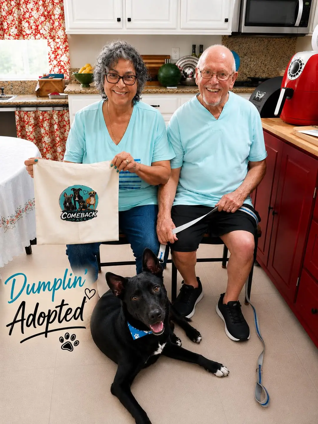 Dumplin', a black dog, lying happily on the floor with his new adopters, an older couple, in their kitchen