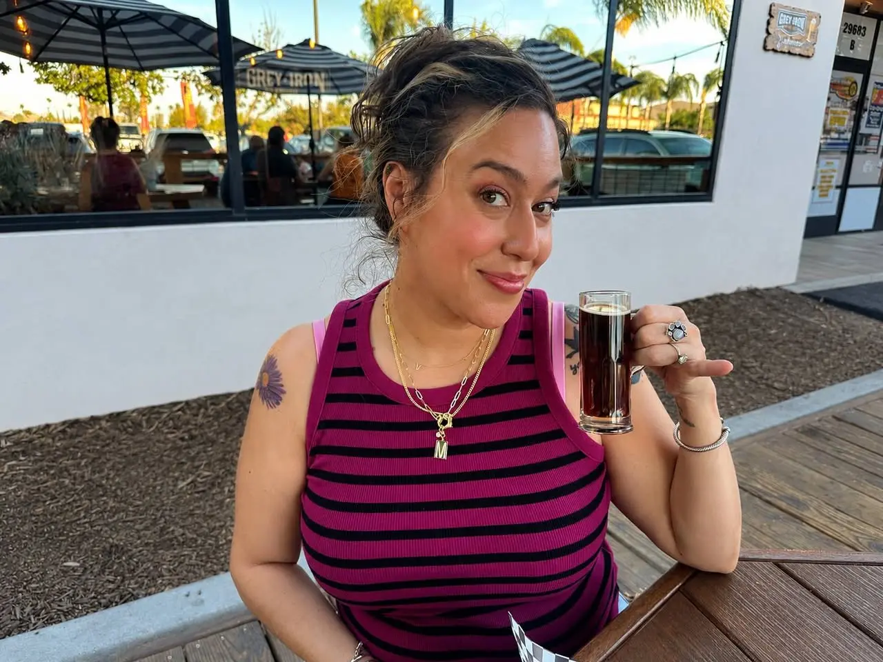 A Comeback Pack team member raising a glass at an outdoor patio table, pinky up, toasting the month's adoptions